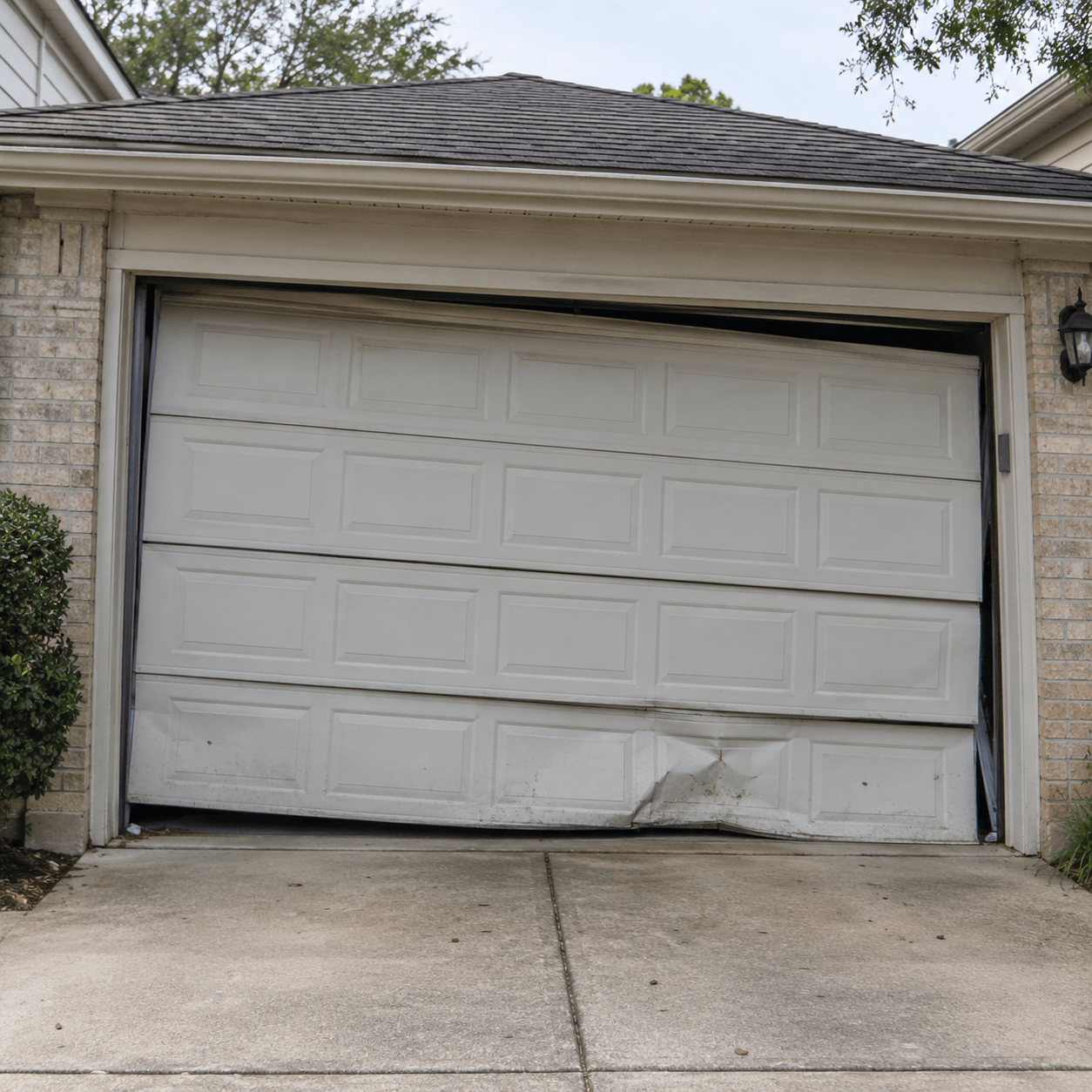 Broken and crooked residential garage door before repair by Garage Door South Houston TX